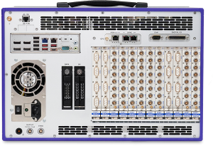 Rear view of an electronic device with multiple ports, connectors, cooling fan, switches, labeled slots, and data input/output modules. The setup suggests industrial or scientific equipment for data acquisition or testing.